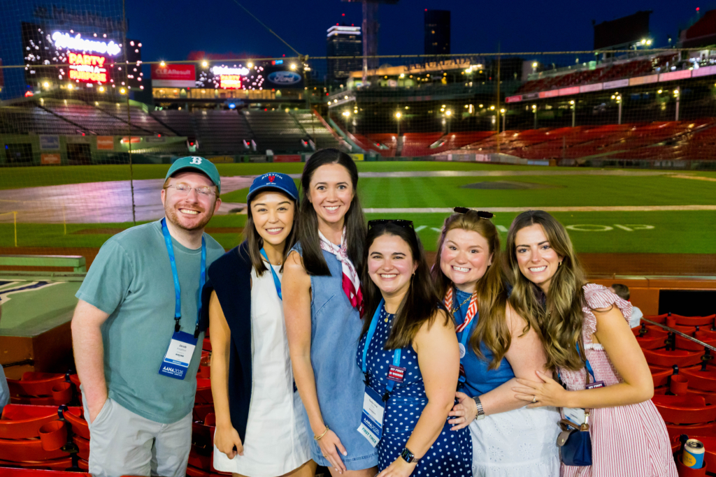 Six attendees pose overlooking the Fenway Park Field in Boston during AANA’s 2026 Party with a Purpose.