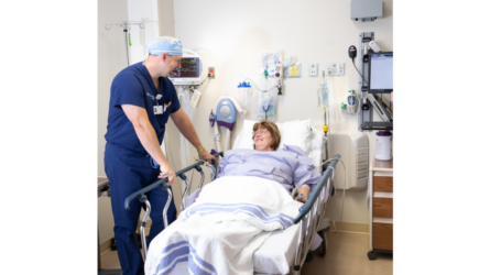 A male CRNA at the bedside of a female patient in a hospital.